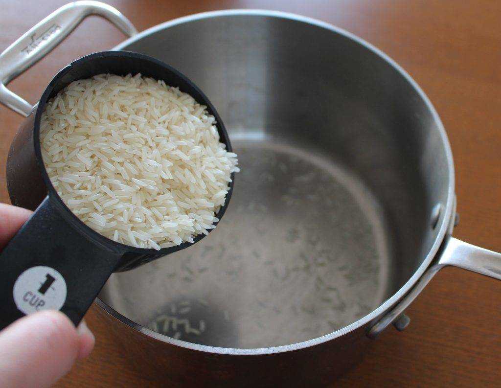 Рис в кипящую или холодную. Рисовая каша в кастрюле. Кастрюля для приготовления риса. Кастрюля с кашей. Высыпаем рис в кастрюлю.